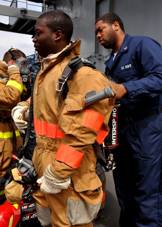 US Navy 100526-N-5483N-051 Personnel Specialist 3rd Class Anthony Hodge helps Yeoman 3rd Class Zachary Williams with a self-contained breathing apparatus during a three-day damage control training course