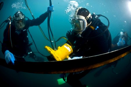 US Navy 100527-N-1134L-003 Navy Diver 2nd Class Sam Elliot, left, assigned to company 26 of Mobile Diving and Salvage Unit (MDSU) 2, instructs a Barbados Coast Guard diver on the proper way to use a hydraulic grinder underwater