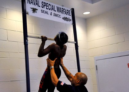 US Navy 100529-N-8689C-519 U.S. Navy SEAL assists a swimmer with pull-ups in the SEAL fitness challenge during the 8th annual National Black Heritage Championship Swim Meet photo