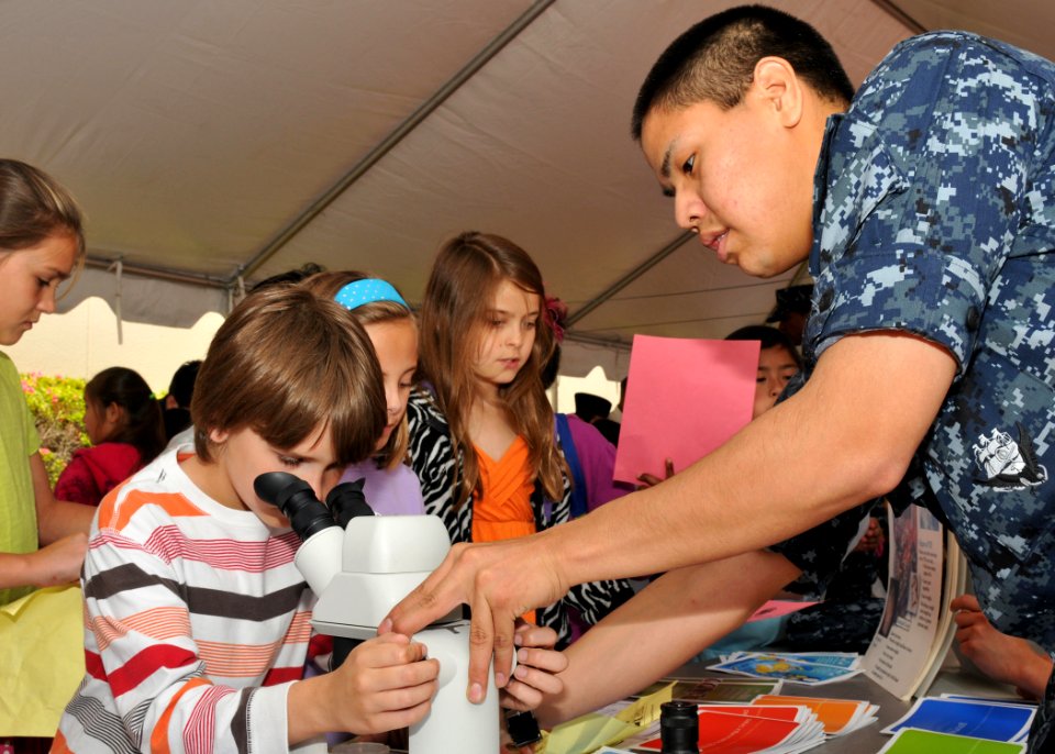 US Navy 100527-N-2013O-003 Hospital Corpsman 3rd Class Brandon Sheaky-Ward, from Anchorag, Ak., helps a girl examine a mosquito under a microscope