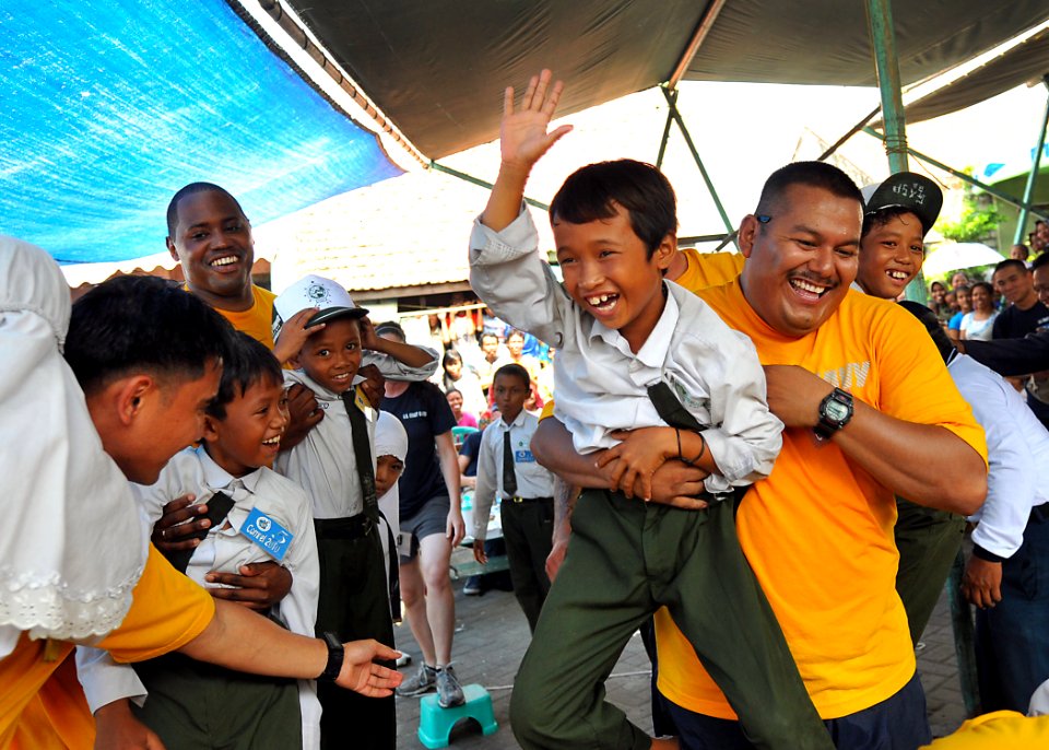 US Navy 100601-N-7643B-428 Master-at-Arms 1st Class Sergio Altamirano carries a boy across the finish line after a race during a community service project