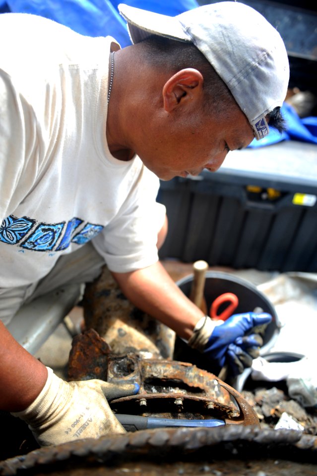 US Navy 100529-N-0413B-014 Dale Maratas, from Joint POW-MIA Personnel Accounting Command (JPAC), scrapes off the engine of an F-4 Phantom that was found and pulled from the water off Quynh Phuong, Vietnam
