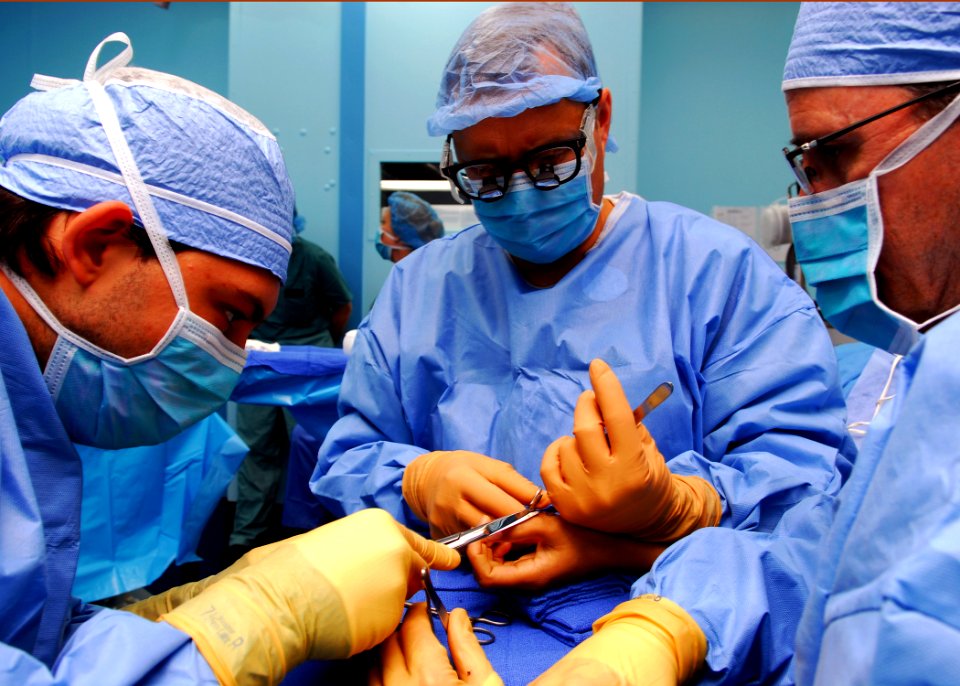 US Navy 100605-N-4044H-085 Adrian Diaz cuts the stitching line as Cmdr. Matthew T. Provencher concludes the surgery of removing an extra thumb from a Vietnamese patient