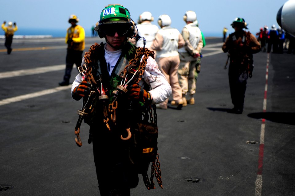 US Navy 100606-N-6604E-138 Aviation Structural Mechanic 3rd Class Parry Williams carries tie-down chains across the flight deck of the aircraft carrier USS Dwight D. Eisenhower (CVN 69)