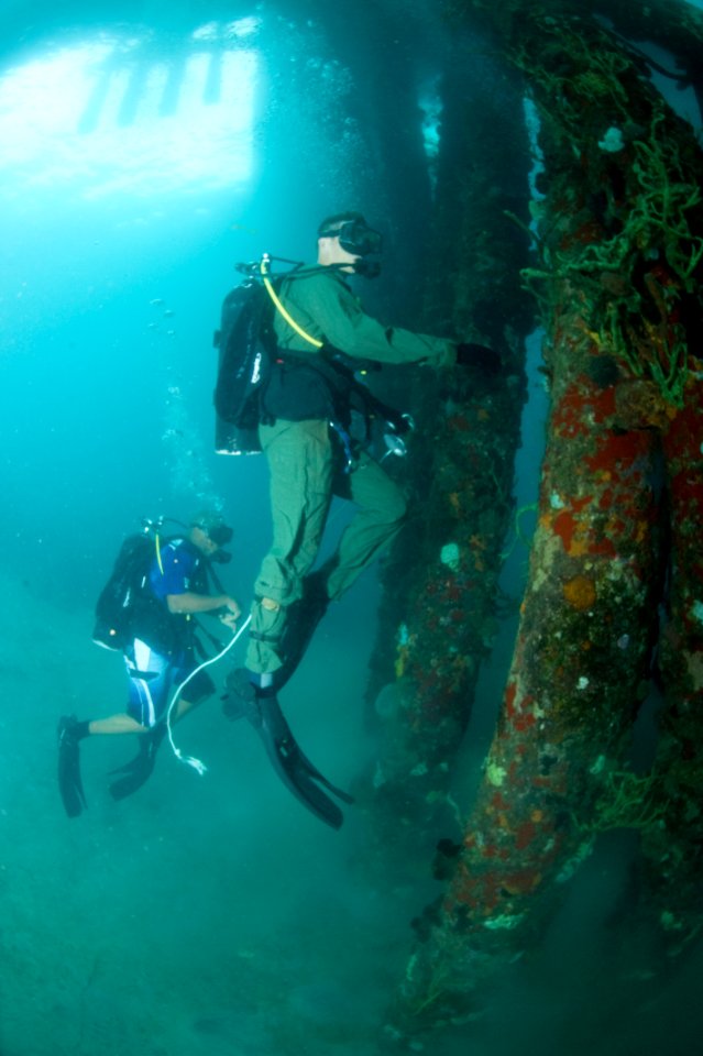US Navy 100607-N-1134L-132 Hospital Corpsman 1st Class Michael Faasen, assigned to Mobile Diving and Salvage Unit (MDSU) 2, and a Regional Security System diver look for damage during a pier inspection