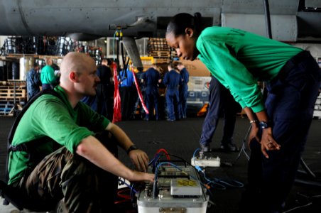 US Navy 100606-N-5085J-002 Aviation Electrician's Mate 3rd Class Shane McClafferty explains the operation of an air data test set to Aircrew Survival Equipmentman Airman Amber Grace aboard the aircraft carrier USS Dwight D. Eis