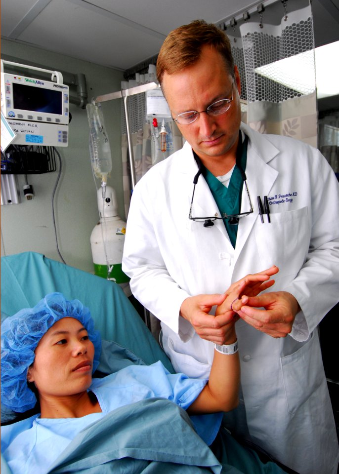 US Navy 100605-N-4044H-018 Cmdr. Matthew T. Provencher examines the hand of a Vietnamese patient before performing surgery to remove an extra thumb
