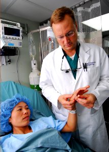 US Navy 100605-N-4044H-018 Cmdr. Matthew T. Provencher examines the hand of a Vietnamese patient before performing surgery to remove an extra thumb