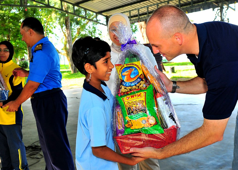 US Navy 100609-N-7643B-073 Lt. Mark Hughes, chaplain for Destroyer Squadron (DESRON) 31, presents a gift basket to a girl from the Rumah Wawasan Children's Home