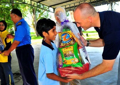 US Navy 100609-N-7643B-073 Lt. Mark Hughes, chaplain for Destroyer Squadron (DESRON) 31, presents a gift basket to a girl from the Rumah Wawasan Children's Home