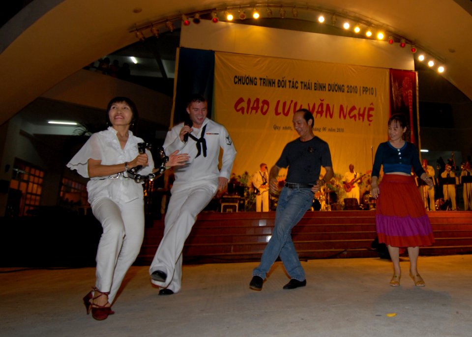 US Navy 100608-N-0209M-001 Musician 3rd Class Anton Dupreez dances with Vietnamese concert attendees at a U.S. Pacific Fleet Band concert at the Nha Van Hoa Lao Dong cultural center in Quy Nhon, Vietnam