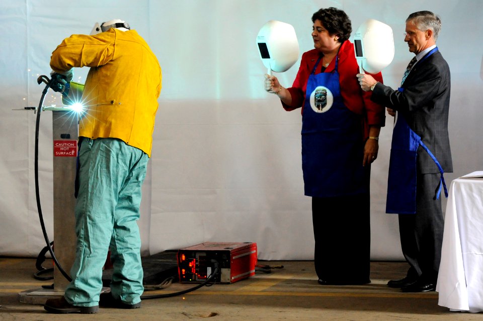 US Navy 100609-N-8467N-001 Allison Stiller and John Casey look on as welder Scott Fanning inscribes Stiller's initials onto a metal plate