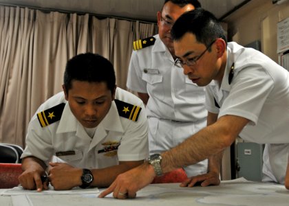 US Navy 100608-N-2218S-002 Lt. j.g. Jason DeJesus, navigator of the guided-missile destroyer USS Mustin (DDG 89), reviews navigation charts with Cmdr. Masahiro Takao and Lt. Kosuke Okazaki