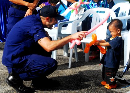 US Navy 100608-N-0995C-183 Coast Guardsman, assigned to the U.S. Coast Guard cutter Mellon (WHEC 717), plays with a child at a community service projec