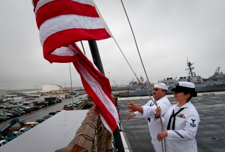 US Navy 100610-N-5319A-031 Hospital Corpsman 2nd Class Mary Schlunsen, right, and Information Systems Technician 3rd Class Vincente Viloria raise the national ensign during morning colors aboard USS New Orleans (LPD 18)