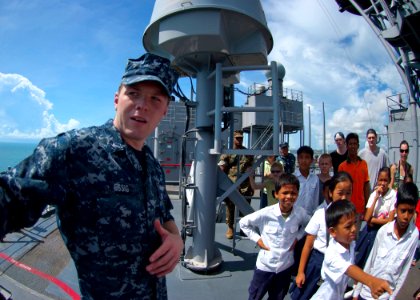 US Navy 100611-N-6770T-174 Operations Specialist 3rd Class Essig explains the ship's defensive weapons to visiting Cambodian orphans