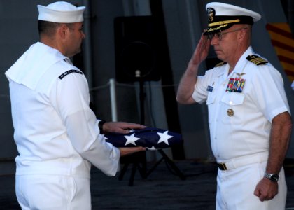 US Navy 100609-N-7908T-310 Capt. Chip Miller salutes Machinist's Mate 1st Class Wesley D. Hatley as he is presented the American flag during a burial at sea for his father photo