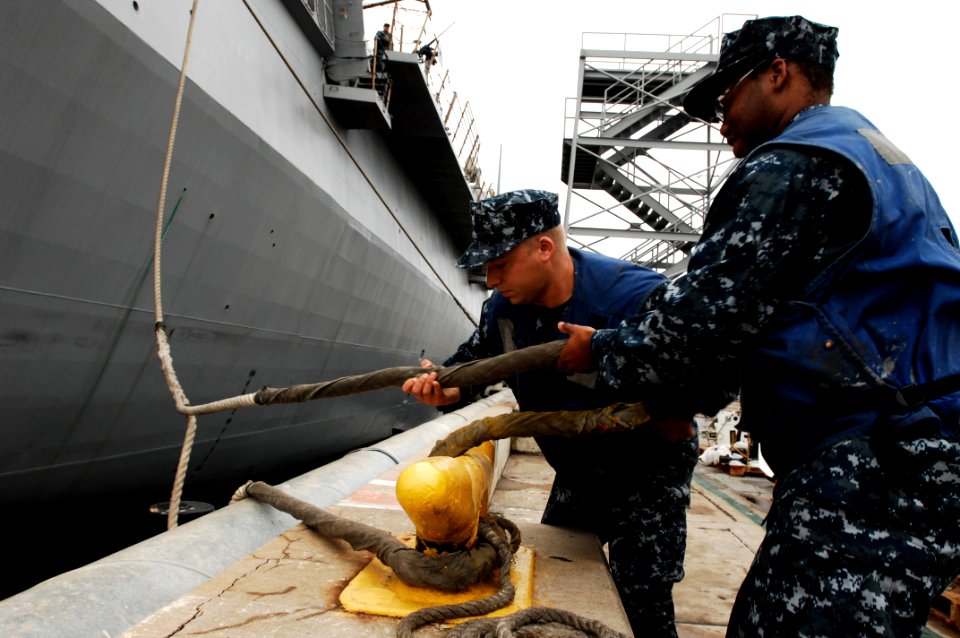 US Navy 100610-N-6477M-795 Quartermaster 3rd Class Cameron Wojak and Seaman Erry Draper assist in removing the mooring lines for the amphibious transport dock ship USS New Orleans (LPD 18)