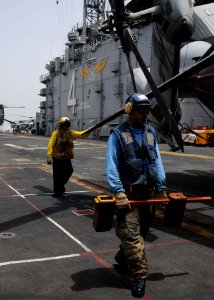 US Navy 100610-N-8936G-066 Airman Eric Brimley, front, from Little Rock, Ark., carries a chock as Aviation Boatswain's Mate (Handler) 3rd Class John Zapata, from El Paso, Texas, holds onto the rotor of a CH-53E Sea Dragon helic