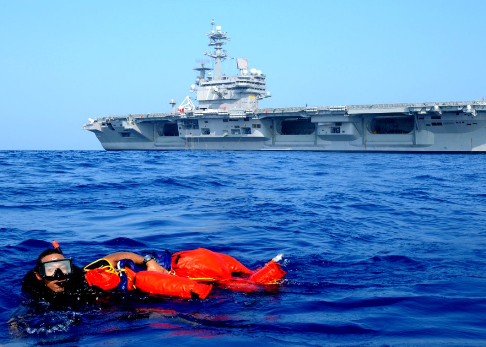 US Navy 100615-N-7908T-868 Search and rescue swimmer Logistics Specialist 2nd Class Wellington G. Bookert swims with Oscarto a rigid-hull inflatable boat during a man overboard recovery drill