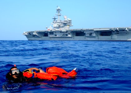 US Navy 100615-N-7908T-868 Search and rescue swimmer Logistics Specialist 2nd Class Wellington G. Bookert swims with Oscarto a rigid-hull inflatable boat during a man overboard recovery drill