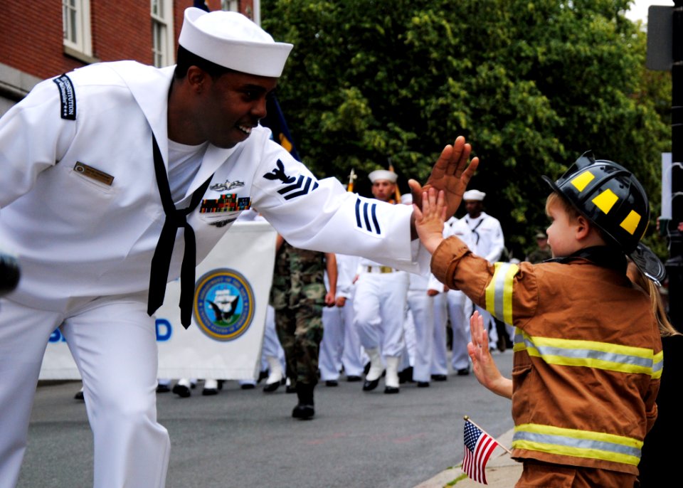 US Navy 100613-N-7642M-337 Electrician's Mate 1st Class Michael Pendergraft, assigned to USS Constitution, high-fives a boy in the crowd during the Bunker Hill Day Parade
