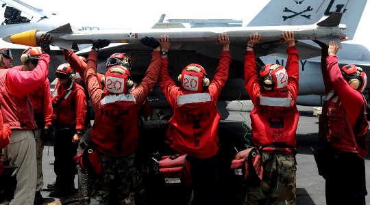 US Navy 100614-N-4236E-219 Aviation Ordnancemen attach ordnance to an F-A-18F Super Hornet assigned to the Jolly Rogers of Strike Fighter Squadron (VFA) 103 on the flight deck of aircraft carrier USS Dwight D. Eisenhower (CVN 6