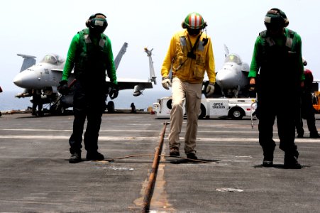 US Navy 100613-N-6604E-223 Lt. Cmdr. Timothy Rhatigan center, inspects an arresting gear wire support with Aviation Boatswain's Mate (Equipment) Airman Nyran Gayle and Airman David Sifuentes