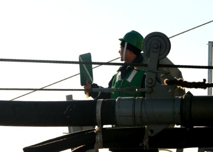 US Navy 100616-N-9301W-185 Boatswain's Mate Seaman Mankong Che signals from the guided-missile frigate USS Klakring (FFG 42) to the Chilean replenishment ship CNS Araucano (AO 53) during an underway replenishment