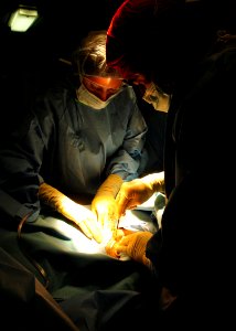 US Navy 100614-N-1226D-130 Cmdr. George Linville, right, surgeon for Commander, Amphibious Squadron 3, makes an incision during the emergency surgery of a Marine aboard the amphibious assault ship USS Peleliu (LHA 5)