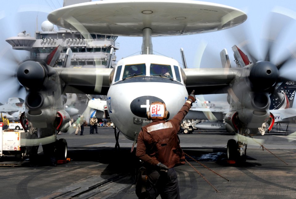 US Navy 100614-N-4236E-098 Aviation Electronics Technician Airman Thomas Buhlinger directs an E-2C Hawkeye assigned to the Bluetails of Airborne Early Warning Squadron (VAW) 121 to start its engines aboard the aircraft carrier