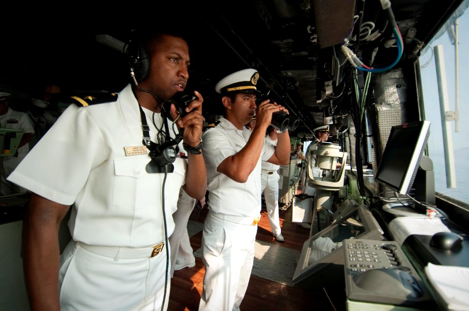 US Navy 100615-N-5319A-007 Ensign Damion Jones speaks to the forward observer on a sound-powered phone next to Mexican navy Lt. Navarrete on the bridge of the amphibious transport dock ship USS New Orleans (LPD 18)