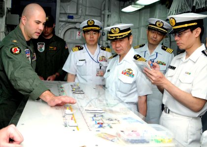 US Navy 100615-N-5215E-167 Lt. Cmdr. Bennett Harris explains the aircraft status board to officers of the Japanese Maritime Self-Defense Force aboard USS Essex (LHD 2)