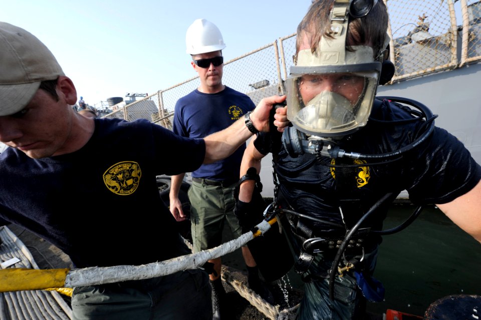 US Navy 100616-N-4776G-785 Navy Diver 1st Class Lars Nilsson is helped out of the water by Navy Diver 2nd Class Taylor Cohee after diving under USS The Sullivans (DDG 68)
