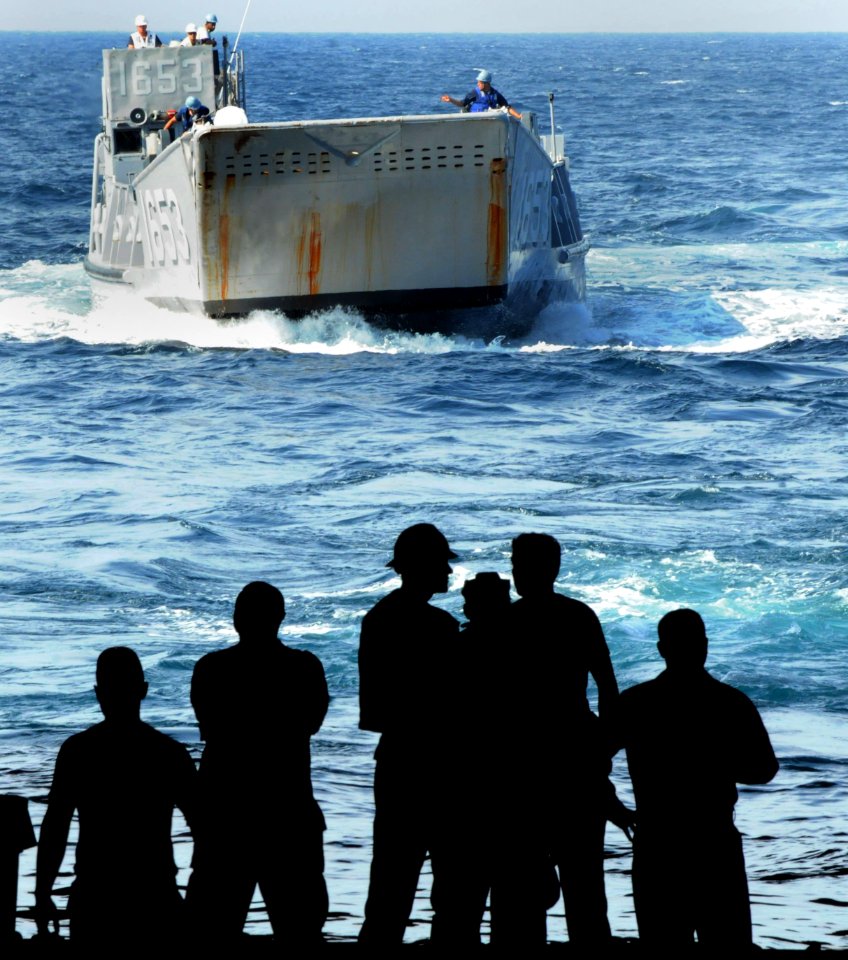 US Navy 100618-N-3852A-994 Sailors and Marines await the arrival of a landing craft utility (LCU) during well deck operations aboard the amphibious assault ship USS Wasp (LHD 1)