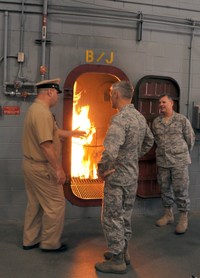 US Navy 100617-N-8848T-783 Chief Machinists Mate Scott Campbell, left, leading chief at USS Chief Fire Fighting Trainer explains how Navy recruits are trained to fight shipboard fires