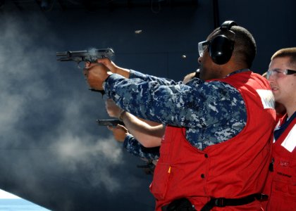 US Navy 100618-N-6632S-301 Aviation Ordnanceman 1st Class Archie L. Gittens fires a pistol for small arms qualification photo