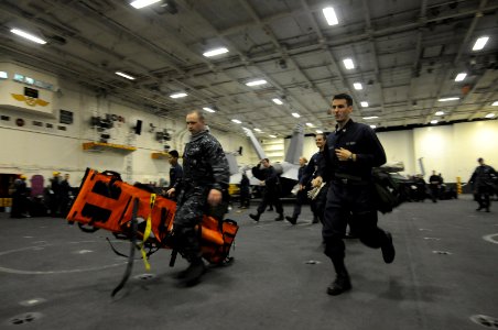 US Navy 100621-N-9132C-257 Stretcher bearers from Repair Locker 7B run to assist a casualty during a general quarters exercise in the hangar bay of the aircraft carrier USS Ronald Reagan (CVN 76)