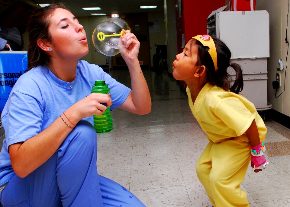 US Navy 100622-N-4044H-013 Kayla Hamrick blows bubbles for a child in the pediatric ward aboard the Military Sealift Command hospital ship USNS Mercy (T-AH 19)