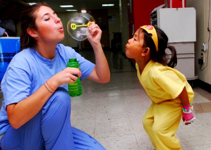 US Navy 100622-N-4044H-013 Kayla Hamrick blows bubbles for a child in the pediatric ward aboard the Military Sealift Command hospital ship USNS Mercy (T-AH 19)
