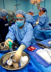 US Navy 100620-N-4044H-105 Hospital Corpsman 3rd Class Dana Doody pours saline solution on laparotomy sponges during a surgery aboard the Military Sealift Command hospital ship USNS Mercy (T-AH 19)