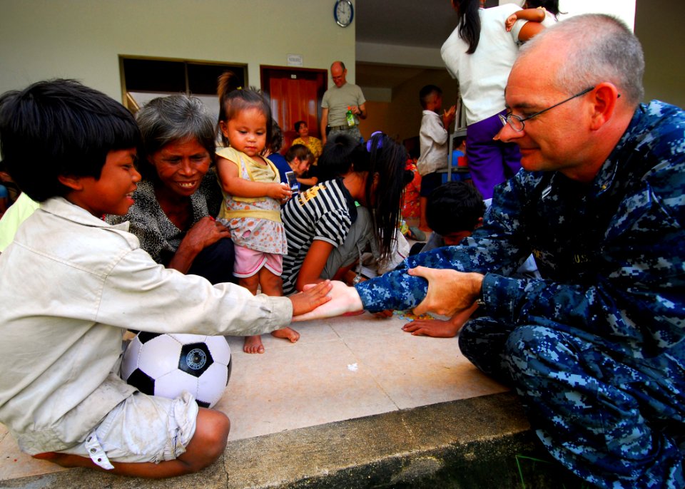US Navy 100623-N-4044H-098 A Cambodian child gives a high-five to Lt. Derrick Horne, a Navy chaplain embarked aboard the Military Sealift Command hospital ship USNS Mercy (T-AH 19), during a community service event