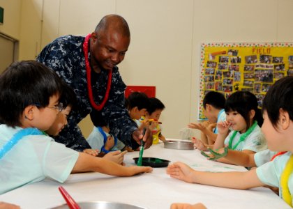 US Navy 100623-N-3215T-063 Culinary Specialist 1st Class Anthony Sykes, from Chicago, paints the hand of a Japanese student from the Shin Yokohama Mama Shinohara Preschool at Richard E. Byrd Elementary School