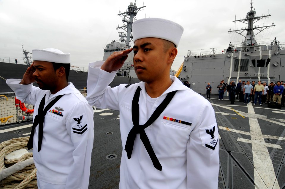 US Navy 100621-N-0775Y-019 Information Systems Technician 3rd Class Kenneth Chan and Operations Specialist 2nd Class Antoine Lattier render a salute after raising the national ensign during morning colors