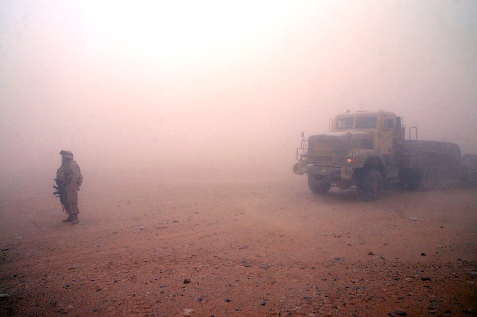 US Navy 100624-N-0475R-502 Chief Equipment Operator Michelle Mathis, assigned to Naval Mobile Construction Battalion (NMCB) 5, guides vehicles during a sandstorm to be staged to build a Mabey-Johnson Bridge