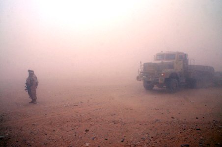 US Navy 100624-N-0475R-502 Chief Equipment Operator Michelle Mathis, assigned to Naval Mobile Construction Battalion (NMCB) 5, guides vehicles during a sandstorm to be staged to build a Mabey-Johnson Bridge