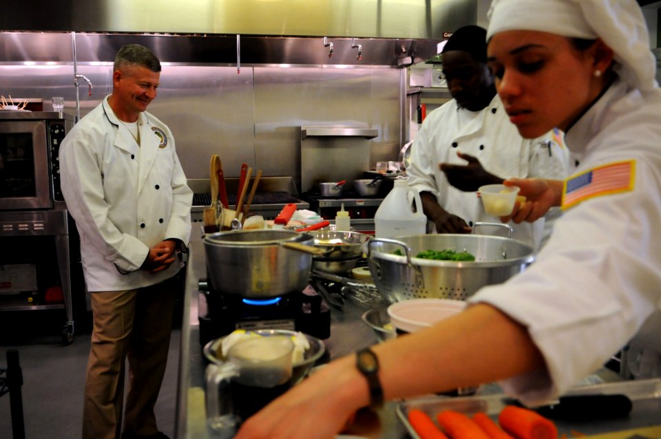 US Navy 100624-N-9818V-050 Master Chief Petty Officer of the Navy Rick West looks on as Culinary Specialist 2nd Class Rodell Hardaway, center, and Culinary Specialist 2nd Class Sonya Angolemmo prepare a meal for the 2nd annual
