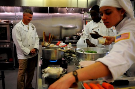 US Navy 100624-N-9818V-050 Master Chief Petty Officer of the Navy Rick West looks on as Culinary Specialist 2nd Class Rodell Hardaway, center, and Culinary Specialist 2nd Class Sonya Angolemmo prepare a meal for the 2nd annual