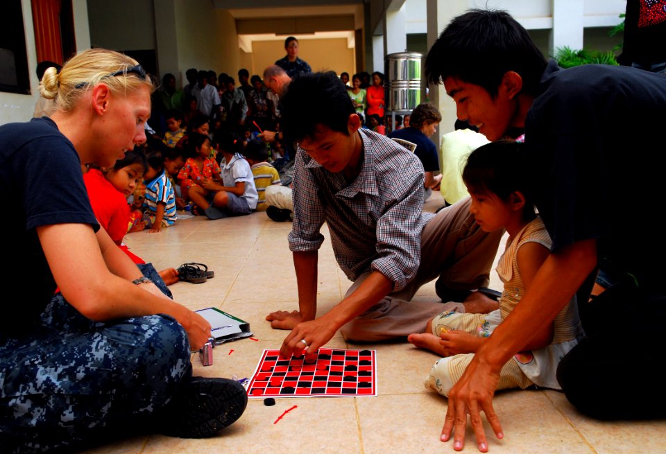 US Navy 100623-N-4044H-047 Religious Programs Specialist 1st Class Jennifer Snow, assigned to the Military Sealift Command hospital ship USNS Mercy (T-AH 19), plays checkers with church members during a community service event