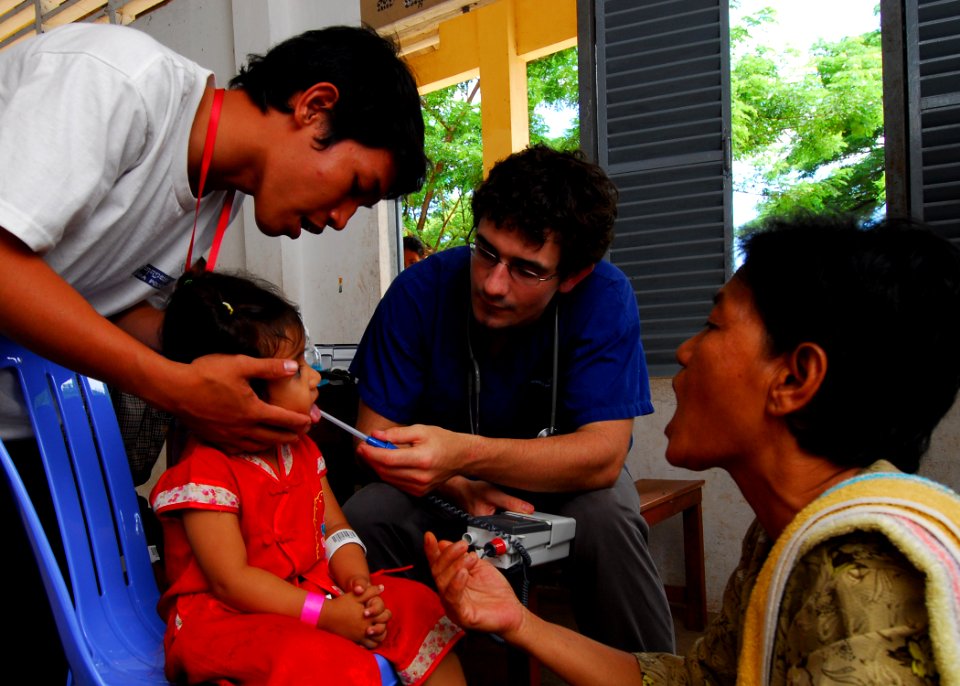 US Navy 100624-N-4044H-086 Philip Drennen, a medical student from New Zealand working at Phnom Penh Hospital, checks a child's temperature during a medical civic action event while the Military Sealift Command hospital ship USN